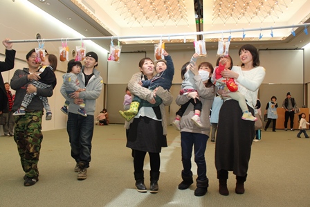 包装されたパンが洗濯バサミで吊るされ、それを子供と一緒に手に取っている保護者らの写真