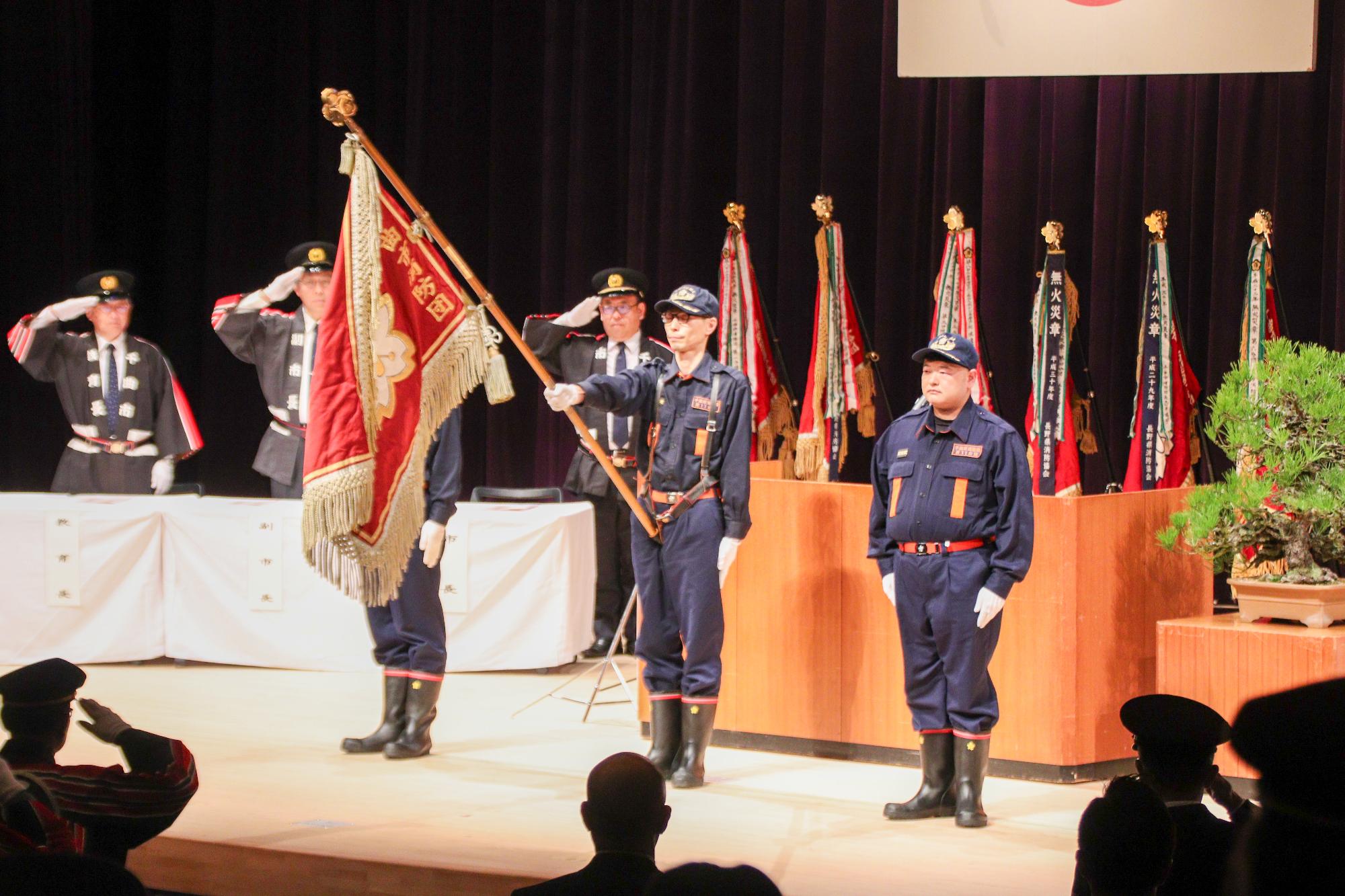 出初式で団旗に敬礼する消防団員