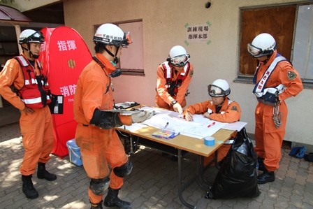 ヘルメットを付けた隊員たちが地図を見ながら作戦を練っている写真