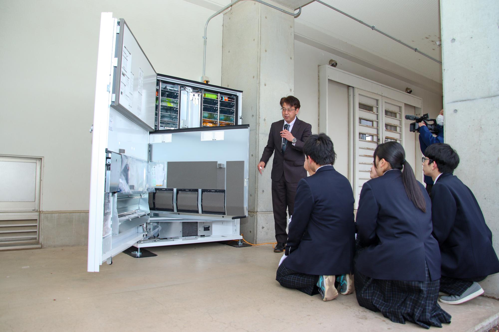 自動販売機設置事業者より屋代中学校の生徒たちに自動販売機の説明をしている様子