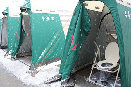 緑色の簡易テントで覆われた災害用トイレの写真
