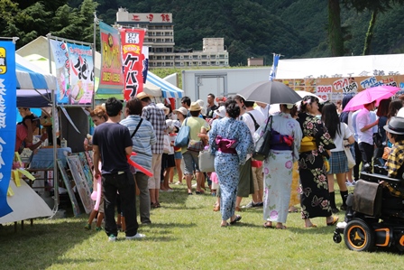 来場者たちが出店のたくさんある会場内を歩いている写真