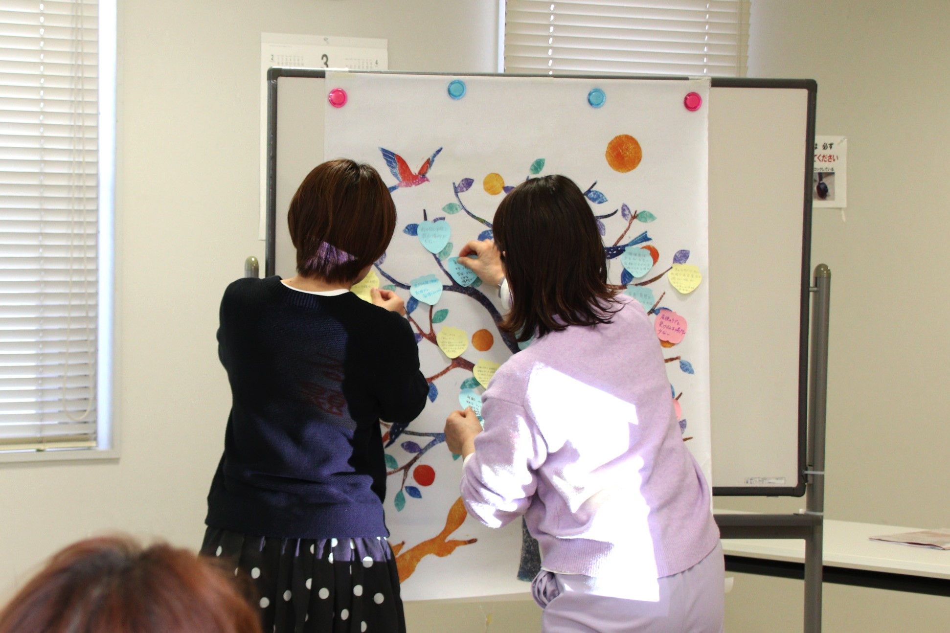 「モヤハレの木」ワークショップで思いを描いた付箋を貼っている参加者の様子