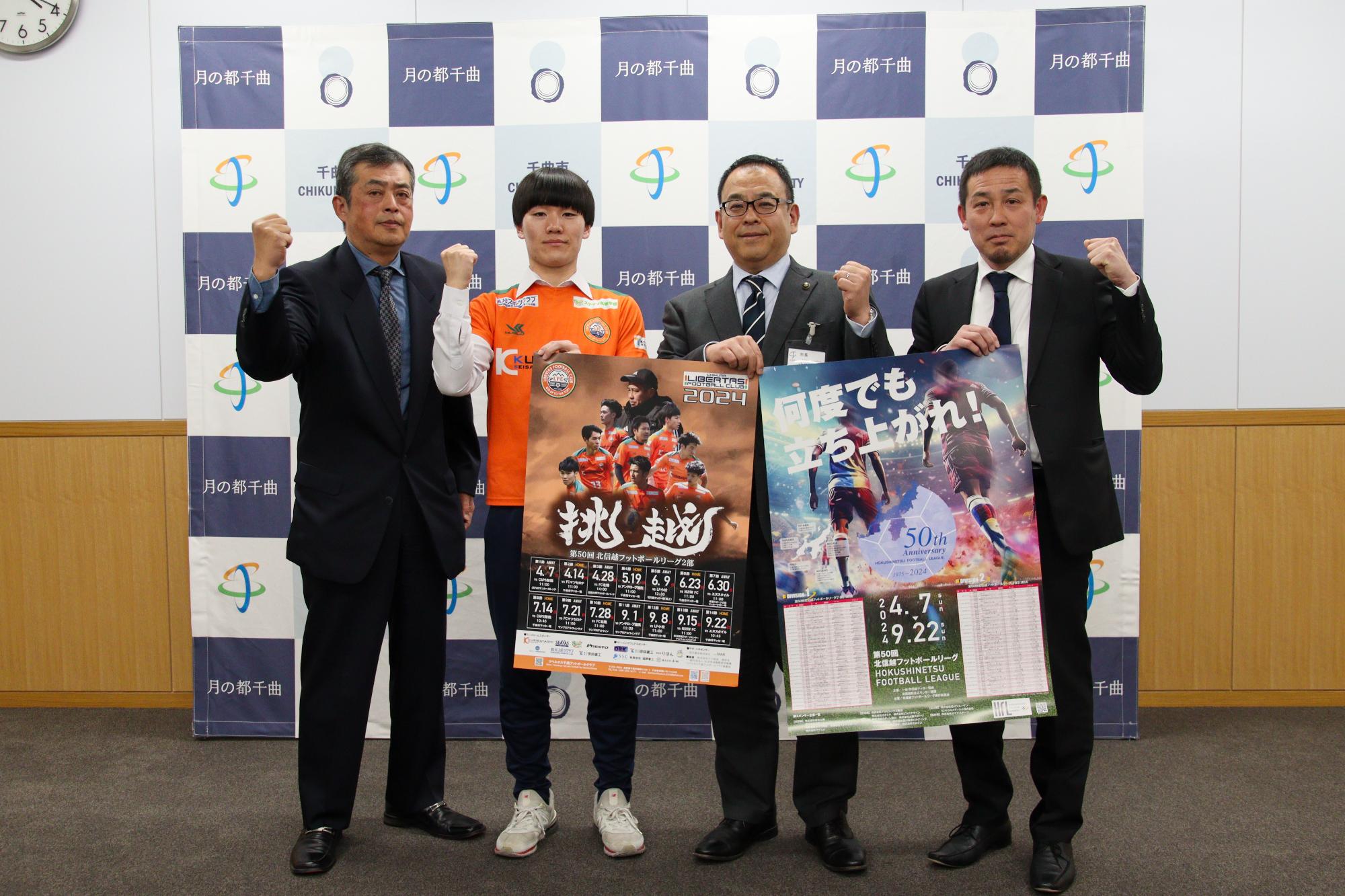 市長とリベルタス千曲の3名が北信越フットボールリーグのポスターを持ちながらガッツポーズ