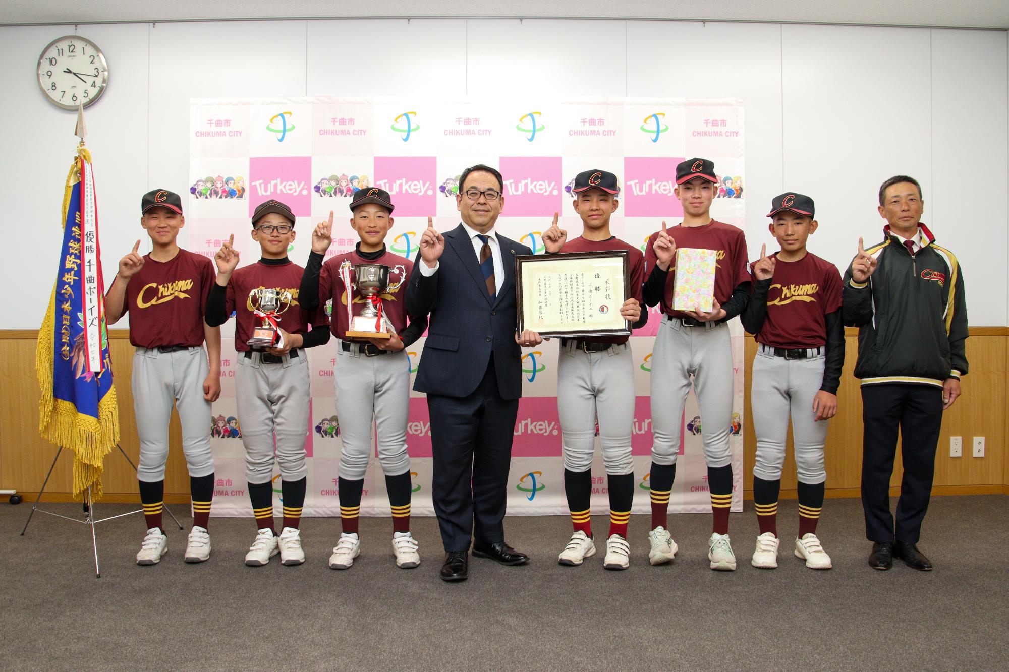 記念撮影の様子。小川市長（中央）とそれをはさんで並ぶ千曲ボーイズの選手と監督たち