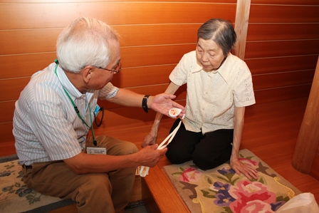 高齢者の女性へ熱中症計を手渡す男性職員の写真