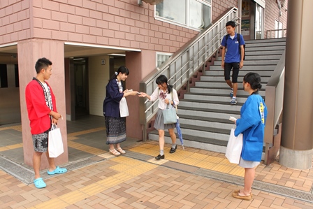 青い半被を着た女性が階段の下で学生にティッシュを手渡している写真