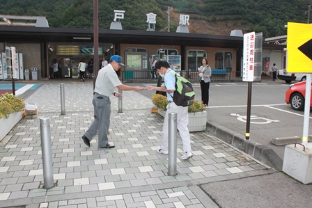 駅舎の近くに立ってチラシを配る男性の写真