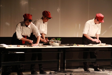 ステージの上で手際よく魚を調理する生徒たちの写真