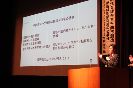 スクリーンに資料のスライドが映し出されている講演会の写真