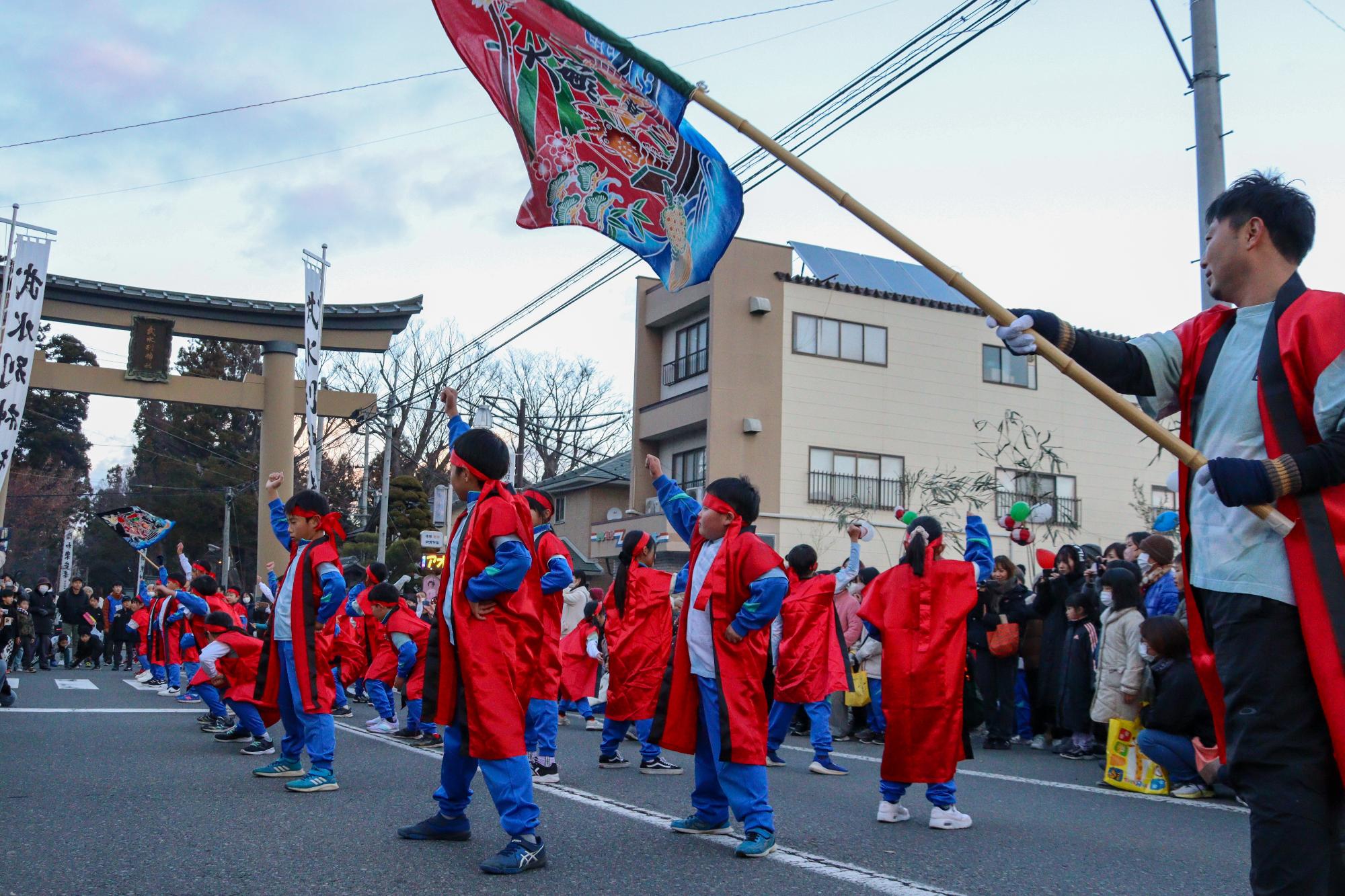 八幡小学校4年生の児童が、大鳥居の前でソーラン節を披露している写真