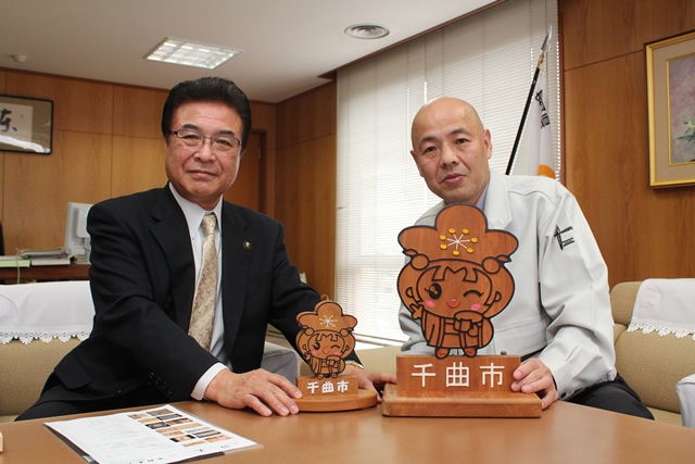 市長と中村さんが木彫りのあん姫をカメラに向けながら笑顔で記念撮影をしている写真