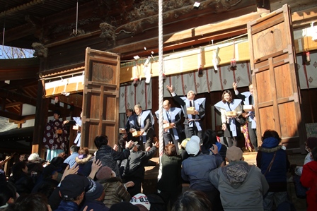 神社の境内で着物を着た氏子たちがいっせいにお菓子を投げている写真