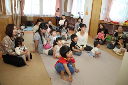 室内で紙芝居を楽しむ親子連れの参加者たちの写真