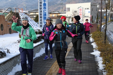 雪が残る道でランナーたちが笑顔で走っている写真