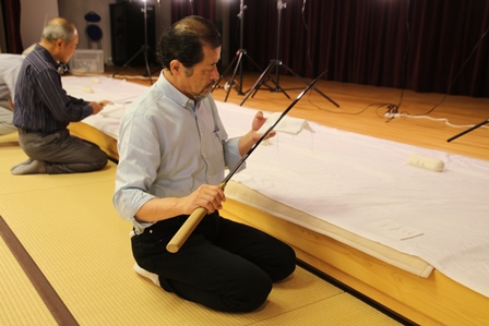 畳の和室に正座をして刀を鑑賞している男性の写真