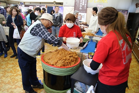 樽に山盛りになった味噌を参加者が掬い取っている写真