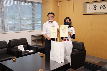 市長と女性選手1名が代表で並んで記念撮影をしている写真