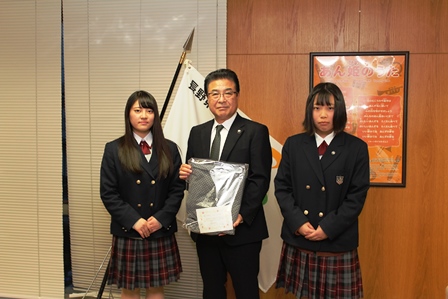 市長が寄贈された介護用パジャマを手に高校の女子生徒2名と並んでいる写真