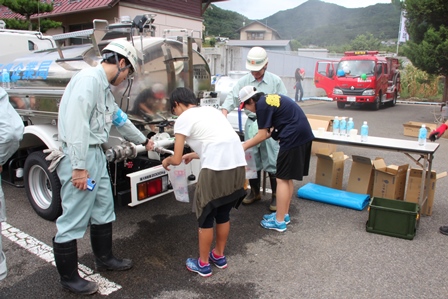 防災訓練で給水者から水を受け取っている人の写真