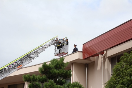 消防車のクレーンに乗った人が屋根に向かっている写真