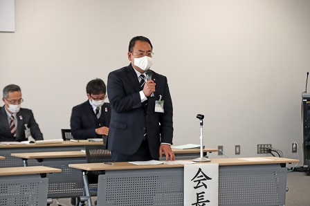 会長席に座っている市長がマイクを手に持ち立って話をしている写真