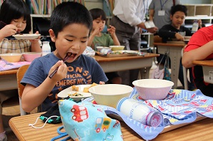 教室内で着席し、給食を食べている児童らの写真