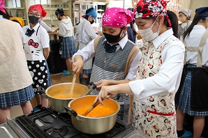 コンロに火をかけあんずを煮込んでいる女子生徒の写真