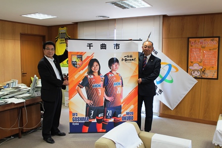 大きなポスターを手に市長と記念撮影をしている社長の写真
