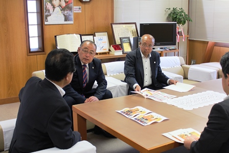市長と堀江社長が資料を見ながら椅子に座ってお話している写真