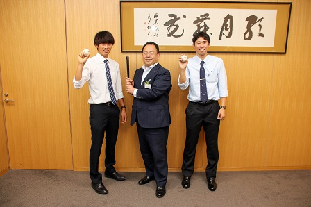 市長、堀口さん、高松さんが野球ボールなどを手に持ち並んで記念撮影をしている写真