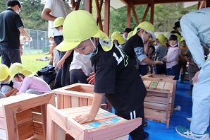 園児が木製のプランターカバーにカラフルな手形をつけている写真