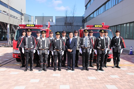 2台の消防車の前で2列に並んで記念撮影をしている市長と消防団員の皆さんの写真