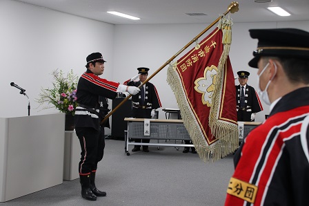 任命式で大きな飾り旗を持っている男性の写真