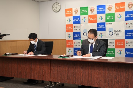 協定書に署名する寿高原食品株式会社の水井代表取締役と小川市長