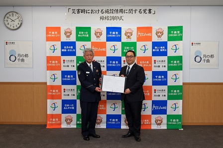 大日方千曲警察署長と小川市長が署名した覚書を手に持って披露する様子