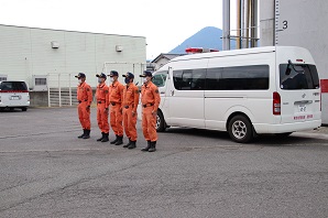 オレンジ色の隊服を着て整列する隊員たちの写真