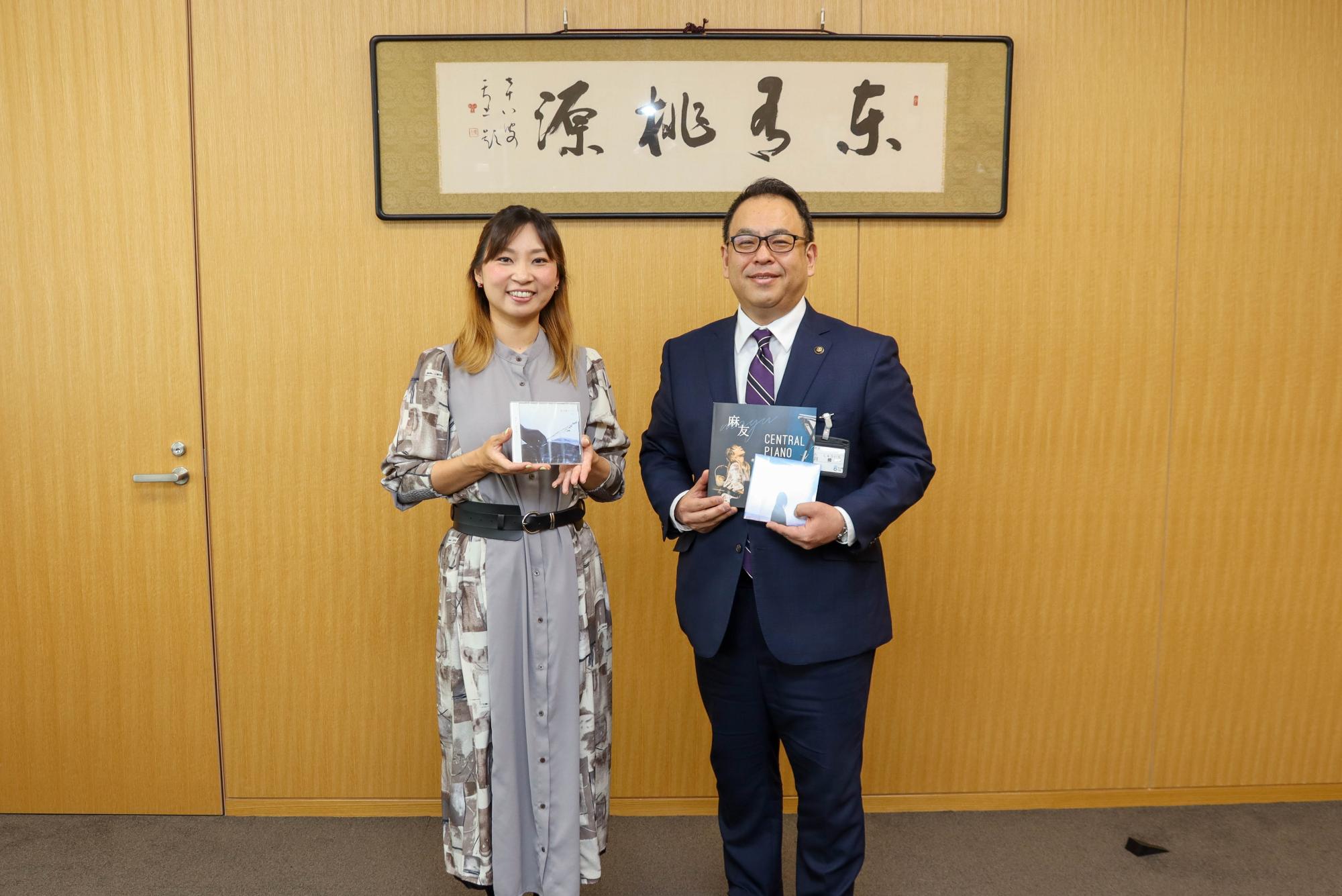 千曲市出身シンガーソングライター麻友さんと小川市長が、麻友さんのCDとライブパンフレットを手に持って記念撮影