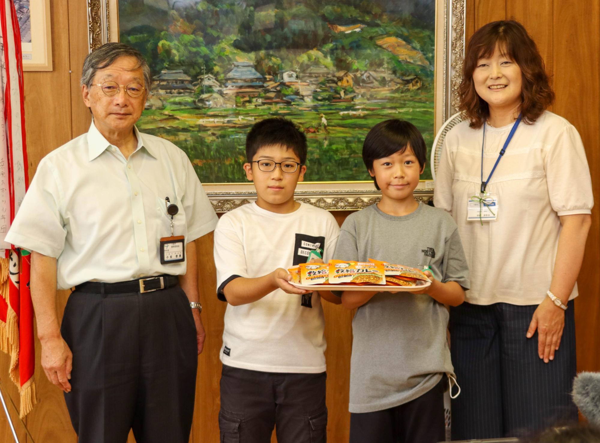 小松教育長、柳澤さん、東海さん、小林校長が非常用給食カレーを持って記念撮影