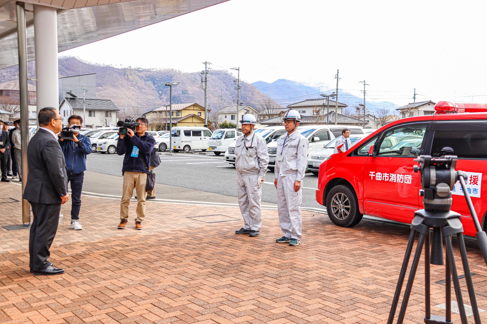 富山県射水市に向かって出発する危機管理防災課の職員2名が「気を付け」をして、小川修一市長から激励の挨拶を受ける様子