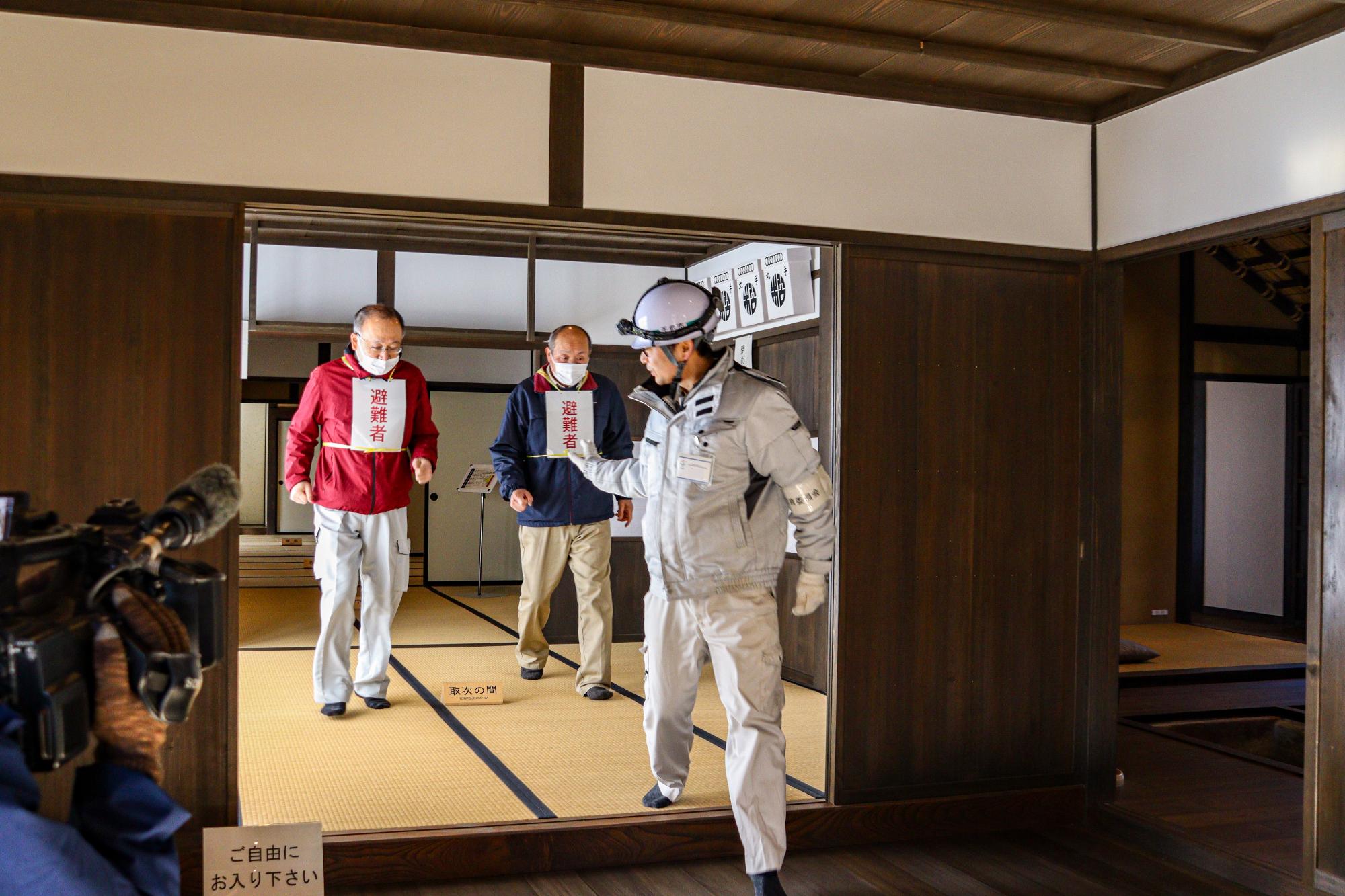 松田邸職員が、松田邸の中で入館者に見立てた避難者2名を館外へ避難誘導する様子