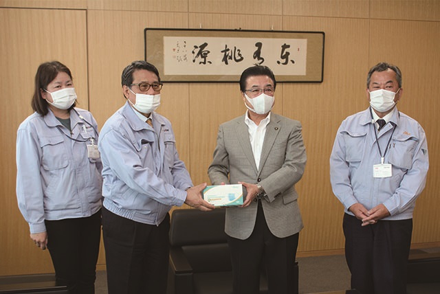市長と長野工業株式会社のみなさんがマスクの箱をカメラに向けて見せながら並んで立っている写真