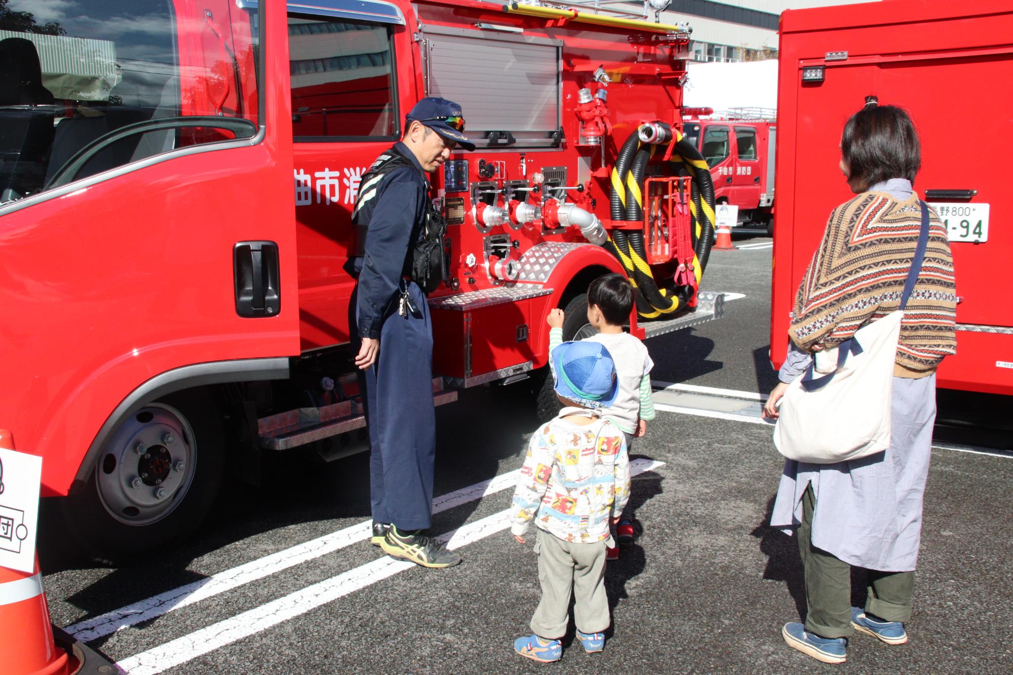 消防団車両の説明を子どもに行なう消防団員