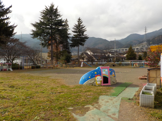 遊具の設置された、芝と砂地に別れた園庭の写真