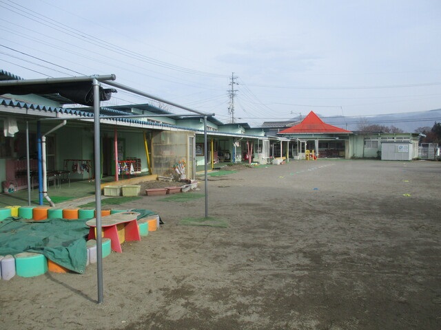 広い土の園庭に向かって、平屋の校舎が並んでいる八幡保育園外観の写真